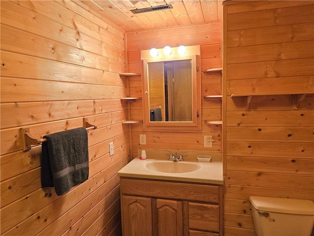 half bath with toilet, wood walls, wood ceiling, and vanity