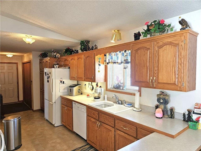 kitchen with brown cabinets, light countertops, a sink, a textured ceiling, and white appliances