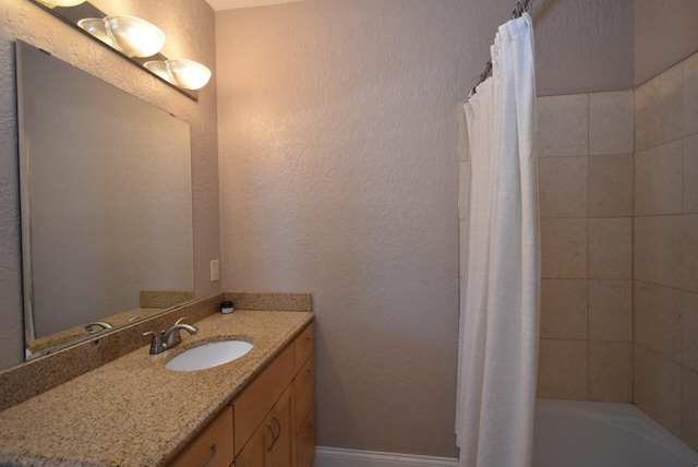 full bathroom featuring shower / tub combo, a textured wall, and vanity