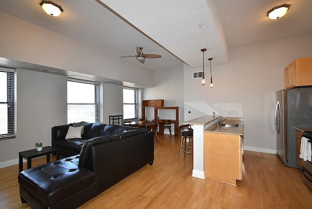 living room featuring light wood finished floors, a ceiling fan, visible vents, and baseboards