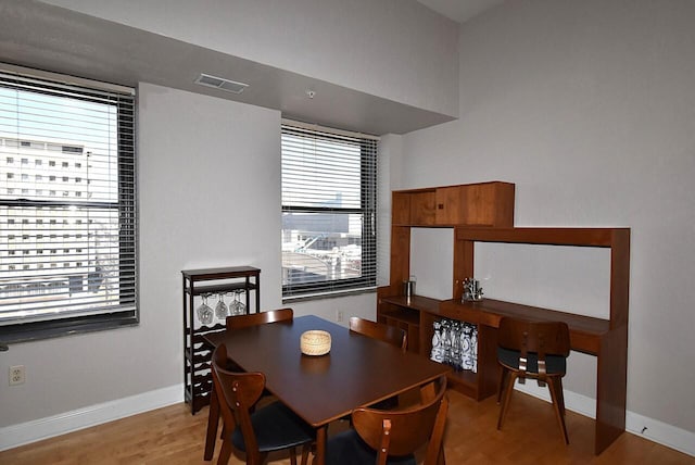 dining area with baseboards, visible vents, and wood finished floors