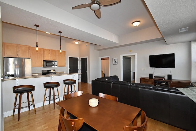 dining room with ceiling fan, a textured ceiling, visible vents, and light wood-style floors