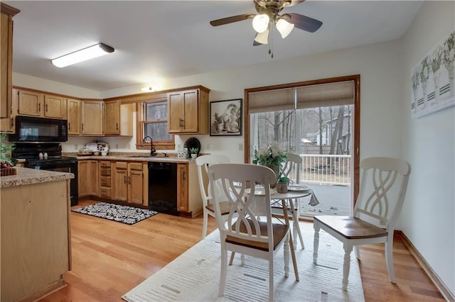 kitchen featuring baseboards, light wood-style flooring, a sink, black appliances, and light countertops