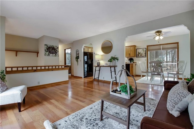 living room featuring baseboards, light wood-style floors, and a ceiling fan