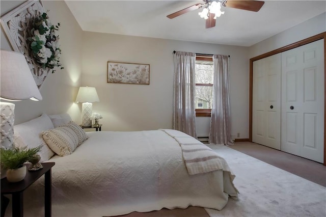 carpeted bedroom with a closet, baseboard heating, and ceiling fan