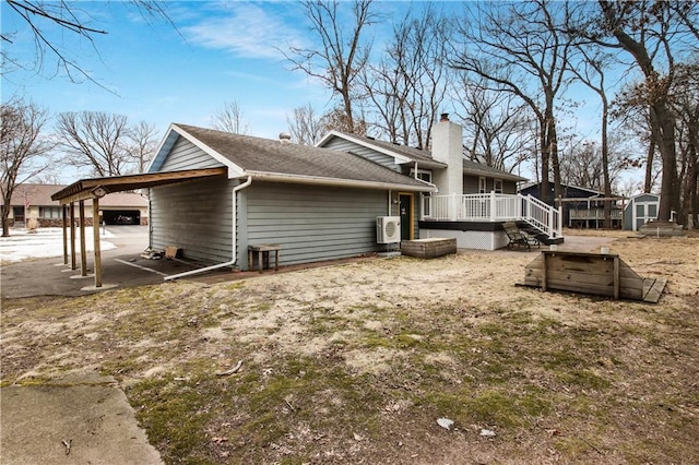 view of side of home with an outbuilding, a shed, a wooden deck, a carport, and a chimney