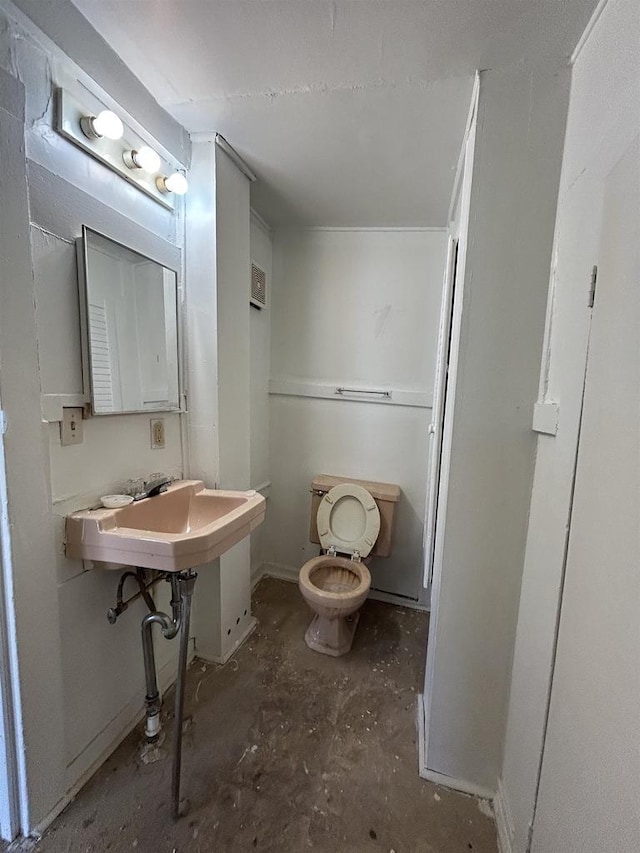 bathroom with toilet and unfinished concrete flooring