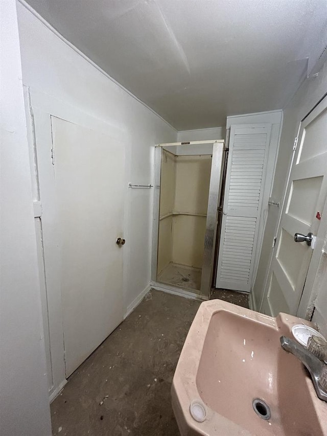 bathroom with a stall shower, a sink, and unfinished concrete flooring