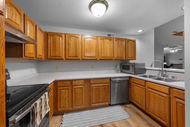 kitchen featuring appliances with stainless steel finishes, brown cabinets, visible vents, and a sink