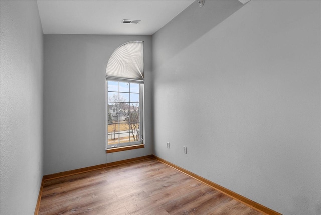 empty room featuring visible vents, baseboards, and wood finished floors