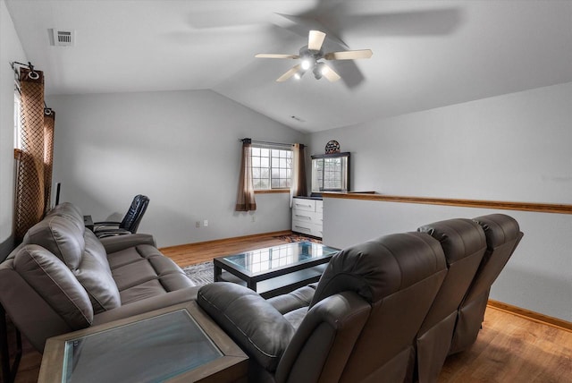 living room featuring a ceiling fan, visible vents, vaulted ceiling, and wood finished floors