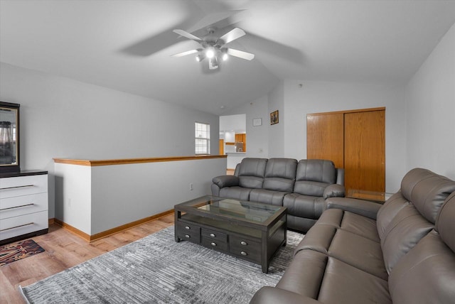 living area with lofted ceiling, baseboards, and light wood-style floors