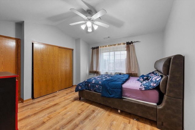 bedroom featuring lofted ceiling, wood finished floors, visible vents, a ceiling fan, and a closet