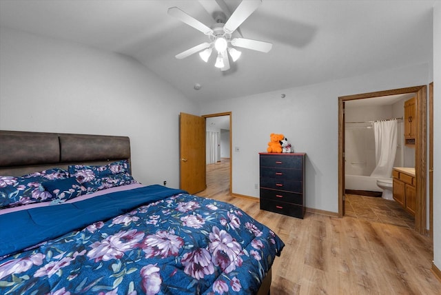 bedroom with light wood finished floors, lofted ceiling, a ceiling fan, ensuite bath, and baseboards