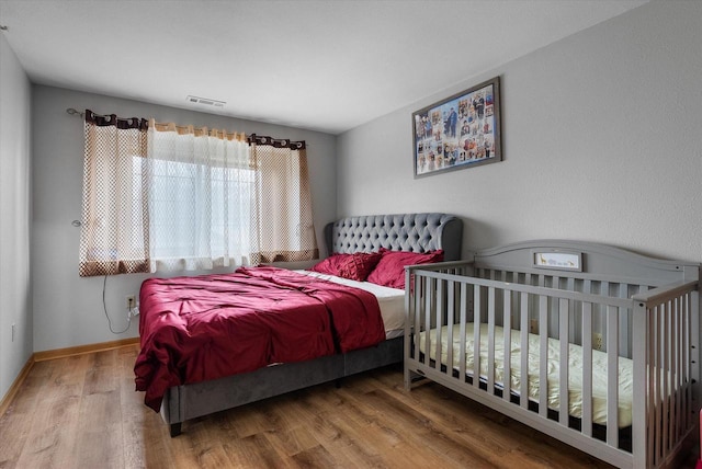 bedroom featuring baseboards, visible vents, and wood finished floors