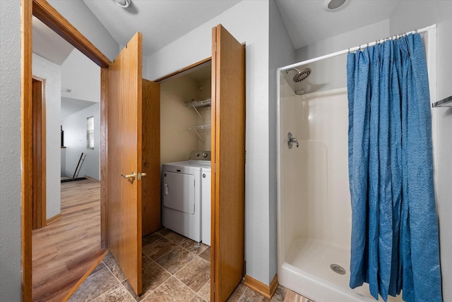 bathroom with a shower stall, baseboards, washer and clothes dryer, and wood finished floors