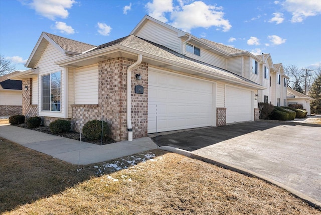 view of side of home featuring concrete driveway, brick siding, an attached garage, and roof with shingles