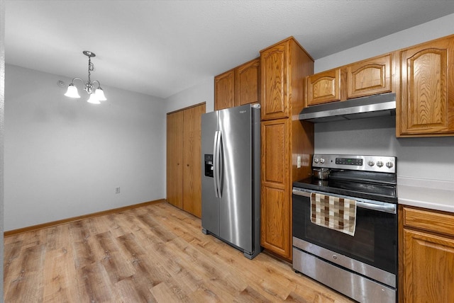 kitchen featuring appliances with stainless steel finishes, a chandelier, brown cabinetry, and under cabinet range hood