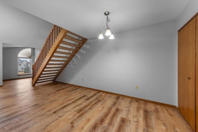 interior space featuring stairs, light wood-style floors, baseboards, and a notable chandelier