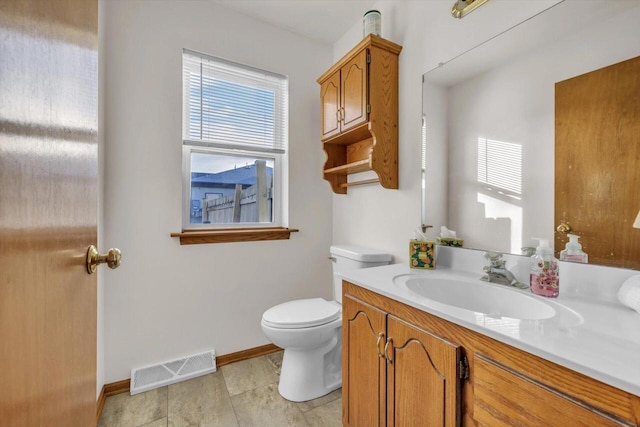 half bathroom with toilet, vanity, visible vents, and baseboards