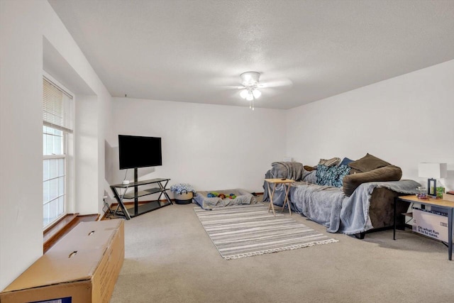 carpeted living room with ceiling fan and a textured ceiling