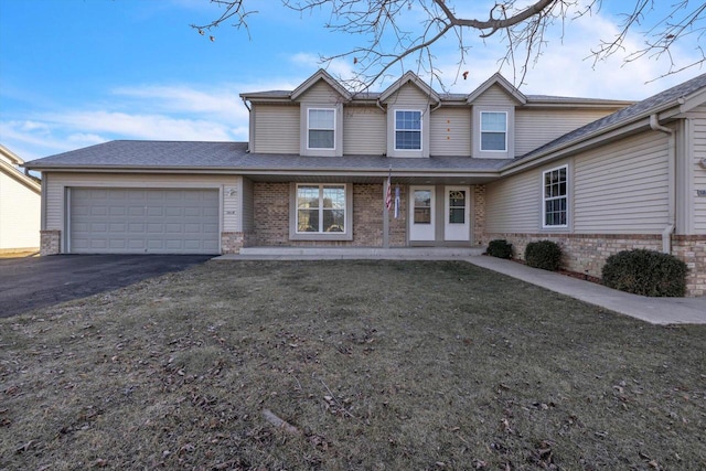 traditional-style house featuring a garage, brick siding, a front lawn, and aphalt driveway