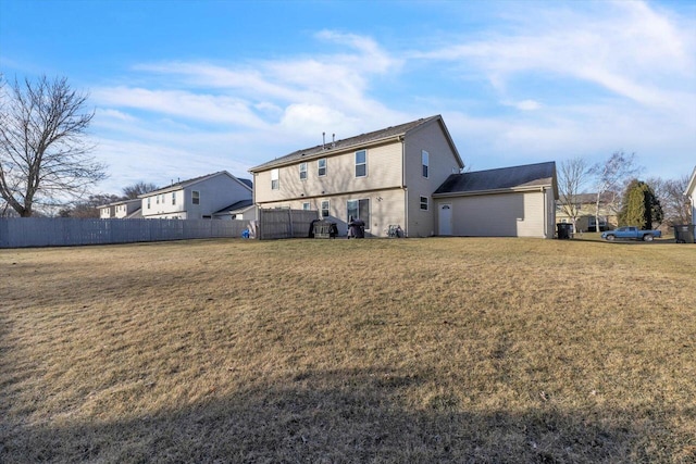 rear view of house with fence and a lawn