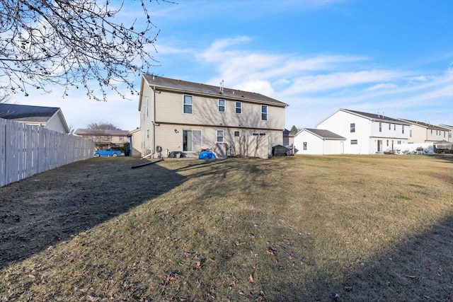 rear view of property featuring a yard and fence