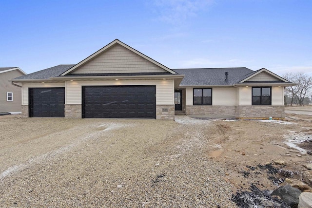 view of front of house featuring driveway, stone siding, an attached garage, and roof with shingles