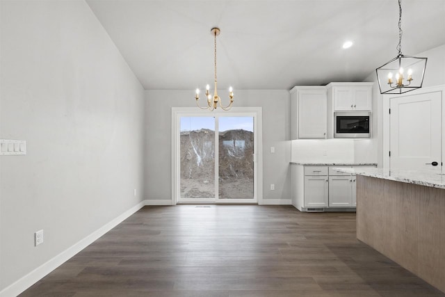 unfurnished dining area featuring baseboards, vaulted ceiling, dark wood finished floors, and an inviting chandelier