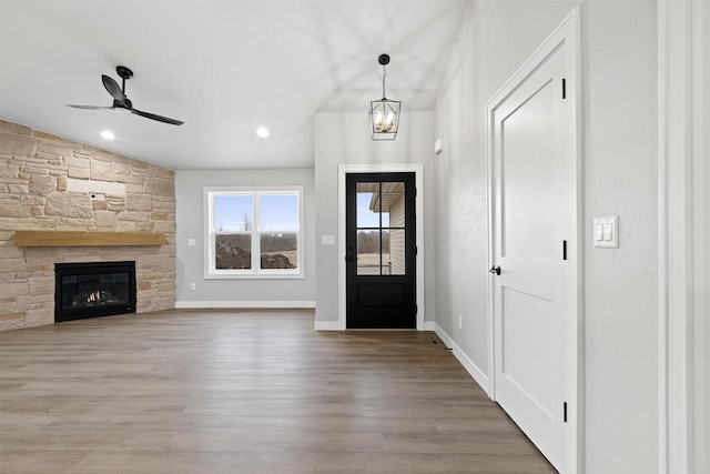 foyer with baseboards, a ceiling fan, lofted ceiling, wood finished floors, and a fireplace