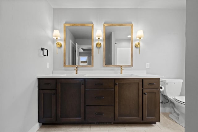 full bath with toilet, double vanity, baseboards, and a sink