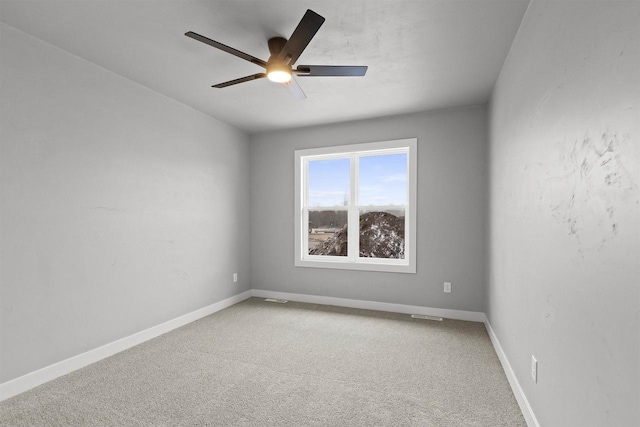 carpeted spare room with ceiling fan, visible vents, and baseboards