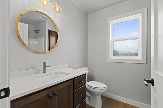 bathroom featuring toilet, wood finished floors, vanity, visible vents, and baseboards