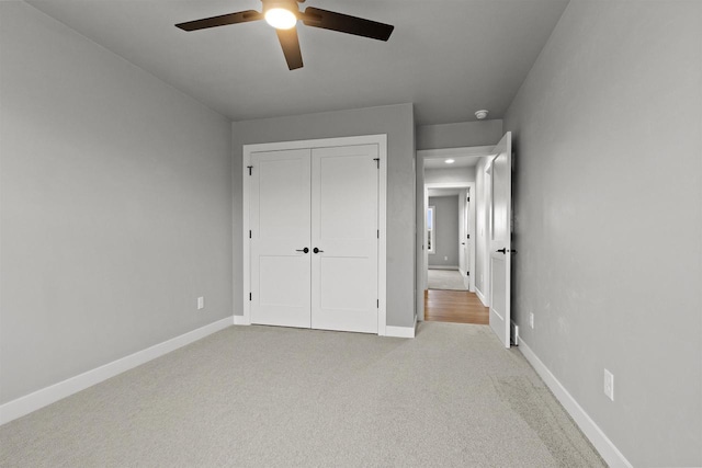 unfurnished bedroom featuring a closet, light carpet, ceiling fan, and baseboards