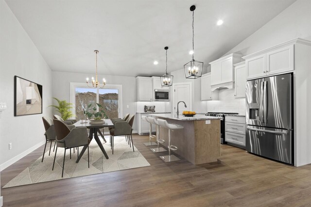 kitchen with stainless steel appliances, dark wood-type flooring, white cabinetry, and an inviting chandelier