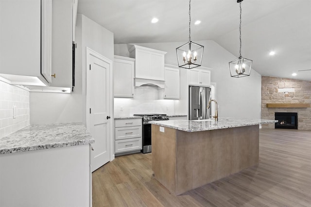 kitchen featuring white cabinets, open floor plan, vaulted ceiling, stainless steel appliances, and light wood-style floors