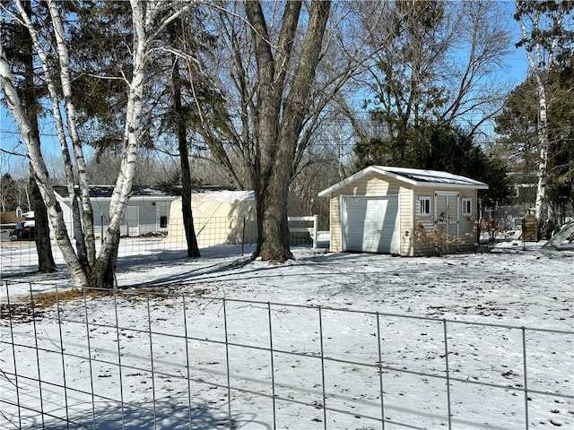 yard covered in snow featuring a garage, an outdoor structure, and fence