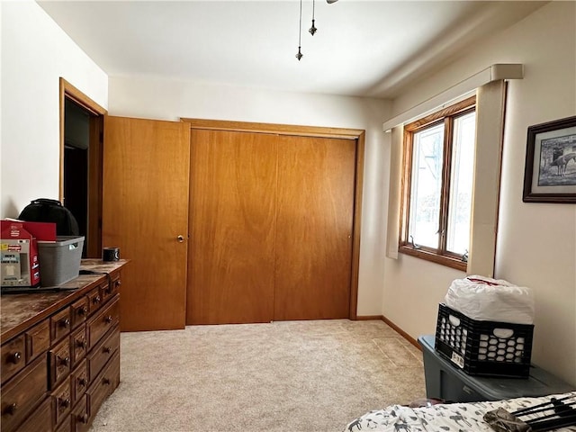 bedroom with light carpet, baseboards, and a closet