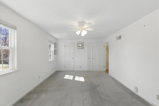 carpeted empty room featuring baseboards, visible vents, and a ceiling fan