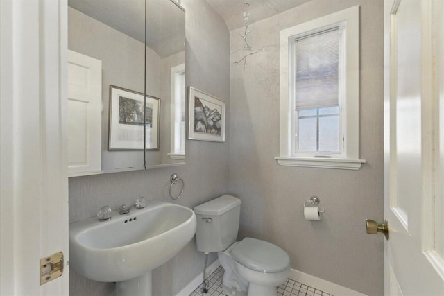 bathroom with tile patterned flooring, baseboards, a sink, and toilet