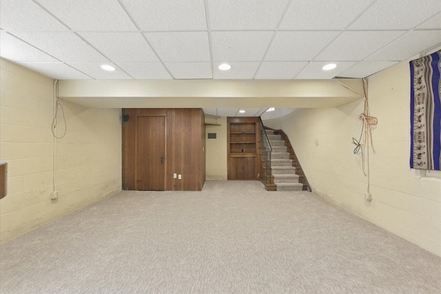 finished basement with stairway, carpet flooring, concrete block wall, and recessed lighting