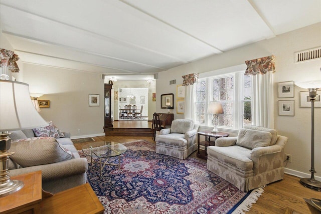 living area featuring baseboards, visible vents, and wood finished floors