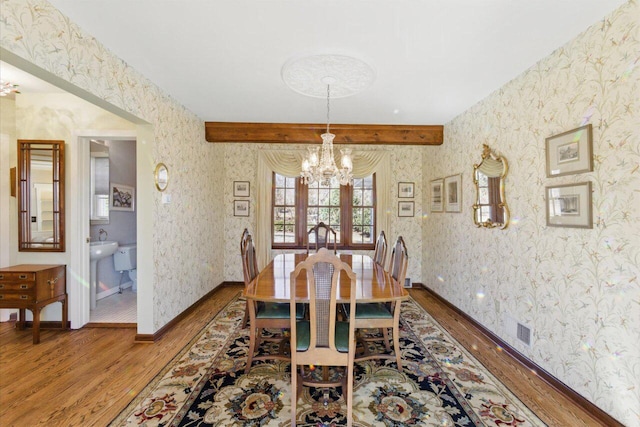 dining area with wood finished floors, an inviting chandelier, and wallpapered walls