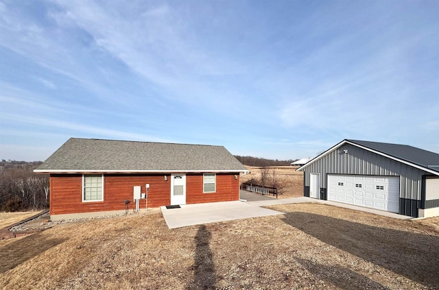 view of front of home featuring roof with shingles, a detached garage, and an outdoor structure