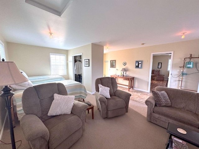 bedroom with light carpet, a closet, a walk in closet, and baseboards