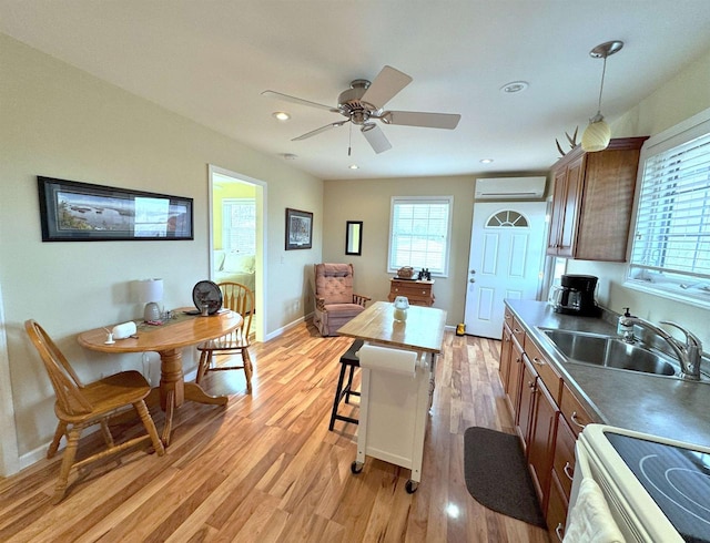 kitchen featuring a sink, baseboards, an AC wall unit, white range with electric stovetop, and light wood finished floors