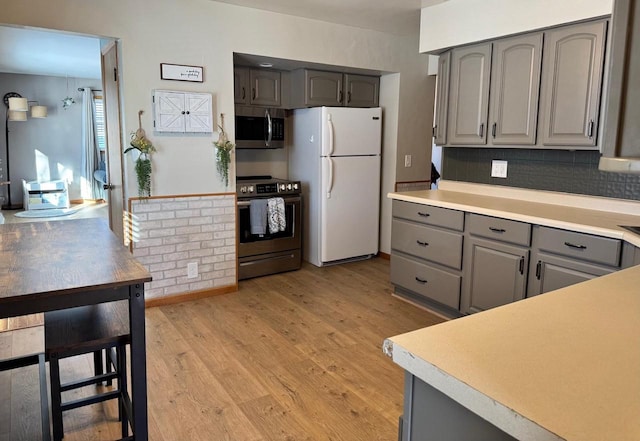 kitchen with stainless steel appliances, gray cabinets, light countertops, and light wood-style flooring