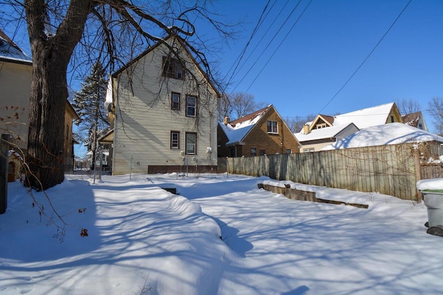 snow covered back of property featuring fence