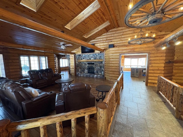 living area with a ceiling fan, stone tile floors, a skylight, a fireplace, and wood ceiling